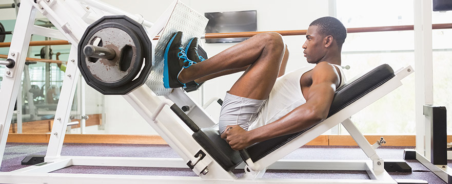 photo of a man using a leg press in a gym