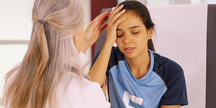 photograph of a girl in a soccer uniform holding her head due to a concussion while receiving concussion physiotherapy