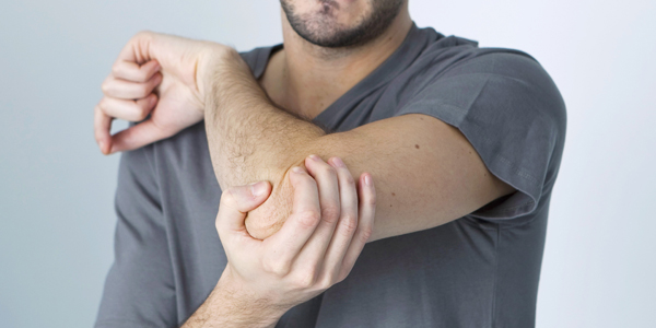 photograph of a man holding his elbow due to tennis elbow pain