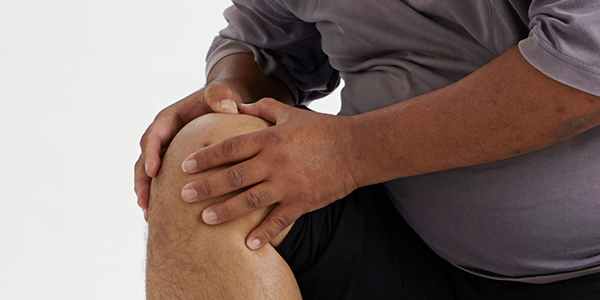 Photograph of man holding knee effected by bursitis.