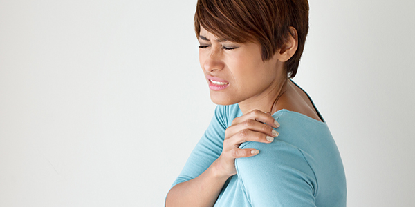 Photograph of woman holding shoulder affected by rotator cuff tendonitis and tendonosis