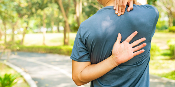 photograph of a man holding his upper back due to degenerative disc disease pain
