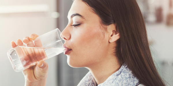 photograph of a woman drinking water to help ease a dehydration headache