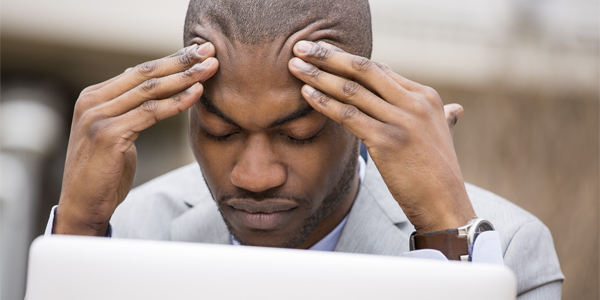 photograph of a man holding his head due to a tension headache